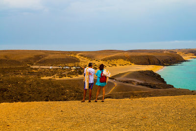 Rear view of people standing on road against sky