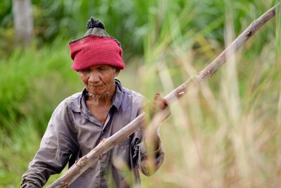 Full length of senior woman holding umbrella against blurred background