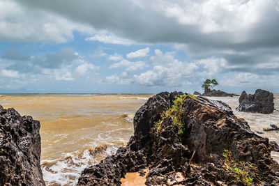 Rock formation on beach against sky