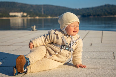 Boy wearing hat while sitting by lake
