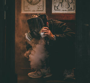 Man wearing gas mask crouching over smoke