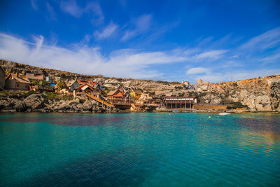 Scenic view of sea by buildings against sky