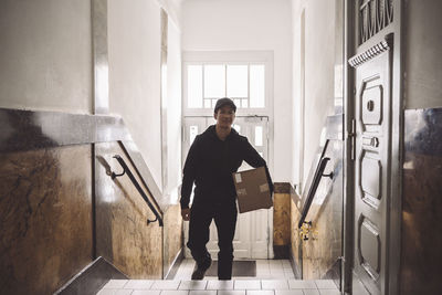 Portrait of delivery man with package climbing staircase