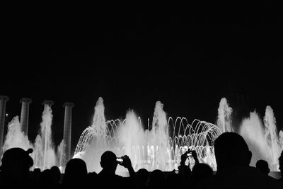 Crowd at music concert against sky at night
