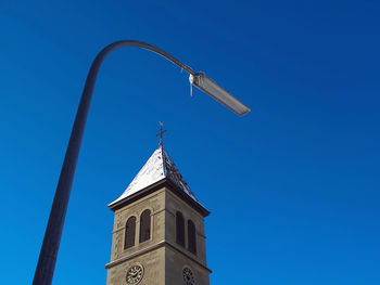 Low angle view of cross on building against clear blue sky