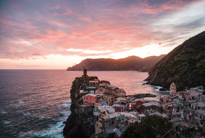 Scenic view of sea by buildings against sky during sunset