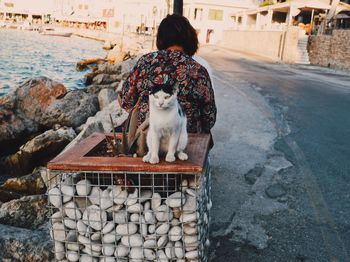 Rear view of woman sitting on street against wall