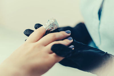 Midsection of beautician decorating finger nails of customer in spa