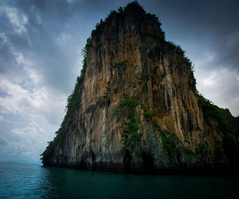 Rock formation by sea against sky