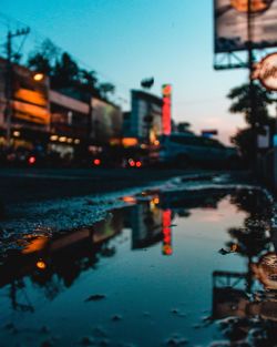 Reflection of illuminated buildings in puddle on street