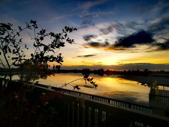 Silhouette bridge over river against sky during sunset