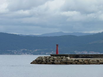 Lighthouse by sea against sky