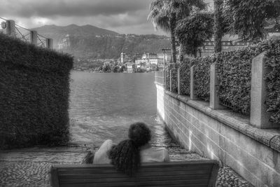 Rear view of woman sitting on bench looking at view