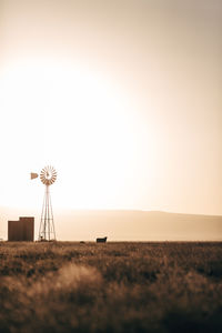 Windmill on field against clear sky during sunset