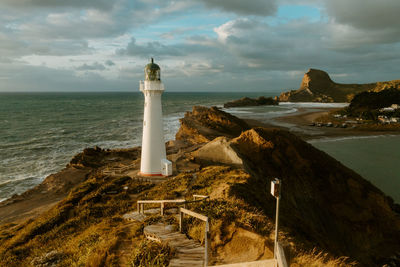 Lighthouse by sea against sky