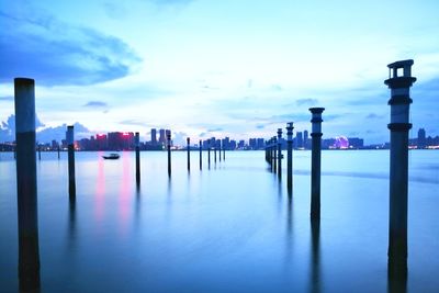 Wooden posts in sea against sky