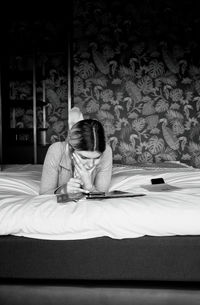 Young woman sitting on bed at home