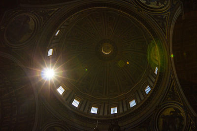 Low angle view of sunlight streaming on building ceiling