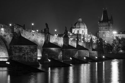 Illuminated bridge over river against sky at night