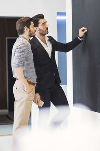 Businessmen discussing at bulletin board in office