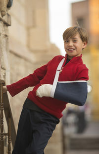 Portrait of smiling boy with orthopedic cast standing outdoors