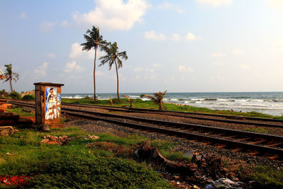 Railroad tracks by sea against sky