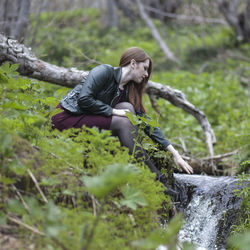 Girl on rock in forest near the river