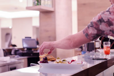 Cropped hand serving food on table in restaurant