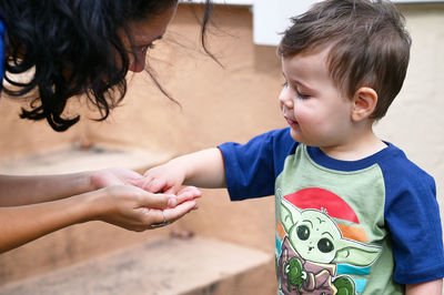 Cute little toddler is playing pebbles with mom on the back porch