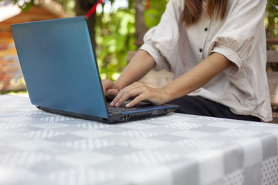 Midsection of woman using laptop at table