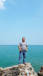 Full length of man standing on rock against sea