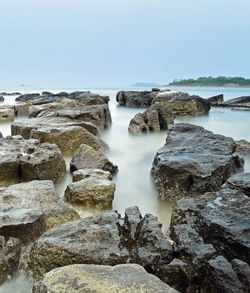 Scenic view of rocks in sea against clear sky