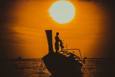 Silhouette man on boat against sea during sunset
