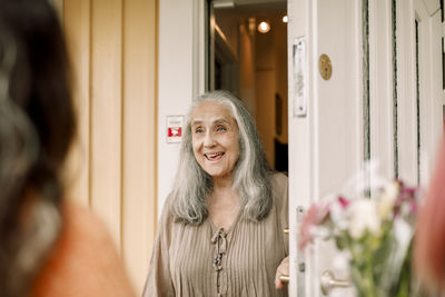 Excited senior woman standing at doorway of house