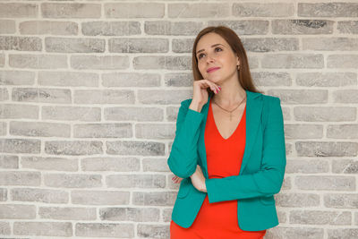 Portrait of woman standing against brick wall