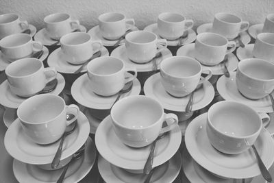 High angle view of white cups and saucers arranged on table