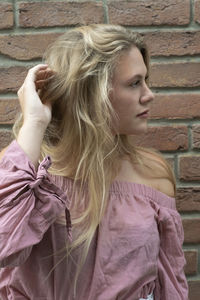 Portrait of woman with arms raised standing against wall