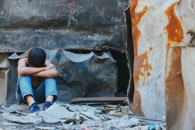 High angle view of boy sitting on abandoned wall