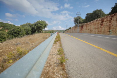 Surface level of road by trees against sky