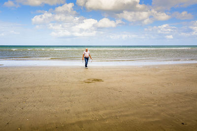Rear view of boy on beach against sky