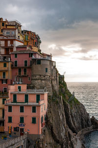 Buildings by sea against sky during sunset