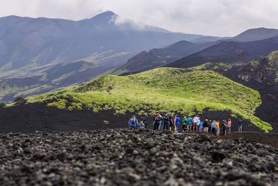 Group of people on landscape against mountain range