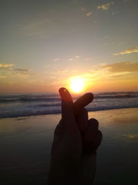 Human hand on beach during sunset