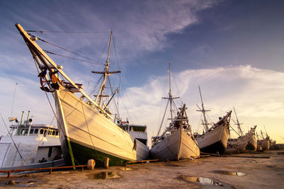 Sailboats moored at harbor against sky