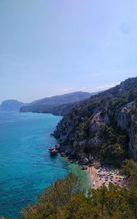 Scenic view of sea and mountains against clear blue sky