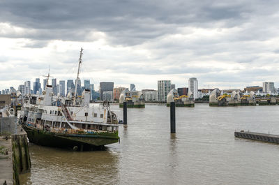 Boats moored at harbor in city against sky