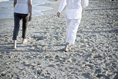 Low section of people walking on beach