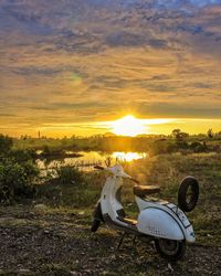 Motorcycle on field against sky during sunset