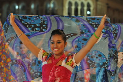 Smiling artist performing traditional dance with scarf during carnival