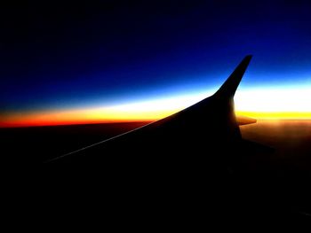 Close-up of silhouette airplane against sky at sunset